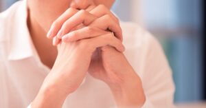 Close-up of a person clasping hands in deep thought, symbolizing stress and Overthinking issues.