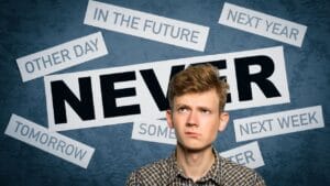 The image features a young man with light brown hair looking upwards with a somewhat skeptical or doubtful expression. He is wearing a plaid shirt. Behind him, against a textured dark blue background, are several white rectangular pieces of paper with black text. The largest piece of paper in the center prominently displays the word "NEVER" in bold, black capital letters. Surrounding it are other phrases suggesting postponement or indefinite timing, such as "IN THE FUTURE," "NEXT YEAR," "OTHER DAY," "TOMORROW," "SOMETIME," and "NEXT WEEK." The overall composition conveys a sense of procrastination or a reluctance to act immediately.