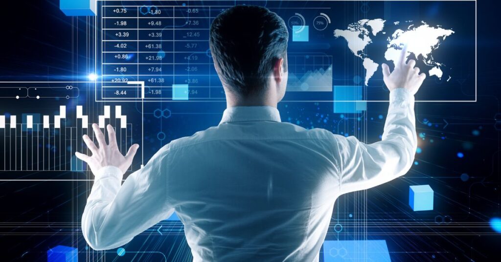 A businessman in a white dress shirt interacts with a futuristic holographic interface displaying global data analytics. His hands hover over a translucent screen showing fluctuating numerical values, bar charts, and a glowing world map, symbolizing real-time monitoring of international markets. The dark blue backdrop features interconnected digital networks and geometric shapes, emphasizing technological sophistication. The scene conveys themes of data-driven decision-making, global business strategy, and seamless integration of human intuition with advanced analytics in a modern corporate environment.