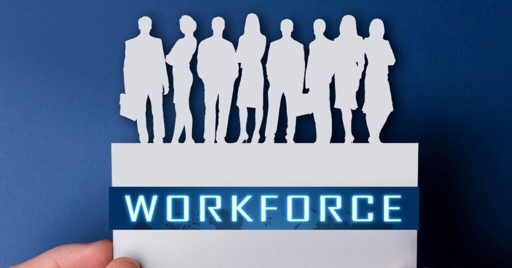 A hand holds a white paper cutout featuring six diverse silhouettes (three men and three women) standing side by side, symbolizing a cohesive workforce. Below the figures, the word 'WORKFORCE' glows in bright blue neon letters against a dark blue rectangular backdrop. The stark contrast between the minimalist human forms and the vibrant text emphasizes themes of unity, collaboration, and the collective strength of a skilled labor force. The solid blue background further highlights the central imagery, reinforcing the importance of workforce dynamics in organizational success.