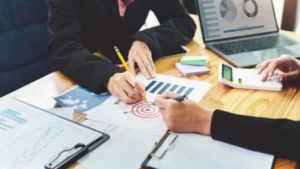 Business team analyzing charts and reports with laptop and calculator for effective project Management.