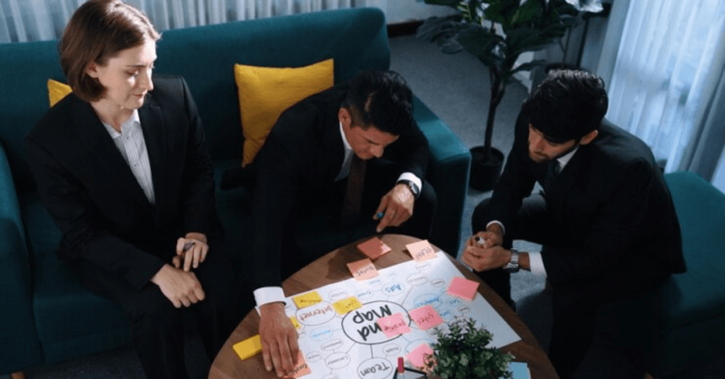A group of three business people sit at a table with sticky notes