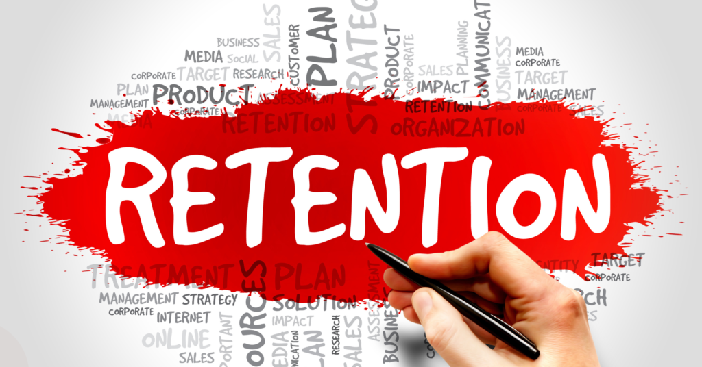 A red splash background featuring the word RETENTION in large white letters. A hand holding a black pen is drawing the word. Surrounding the central text are smaller gray words related to business and management, such as PLAN, STRATEGY, MANAGEMENT, TARGET, and SALES.