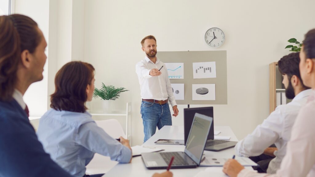 "Business coach using charts to measure ROI from business coaching during office presentation