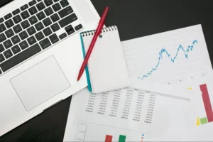 Laptop with financial charts, notebook, and pen representing business planning and growth strategy