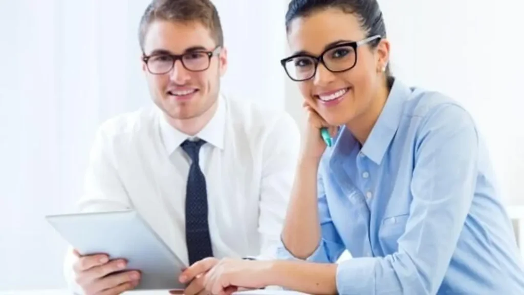 A smiling male and female professional working together, illustrating Why Choose a Certified Business Coach in Toronto.